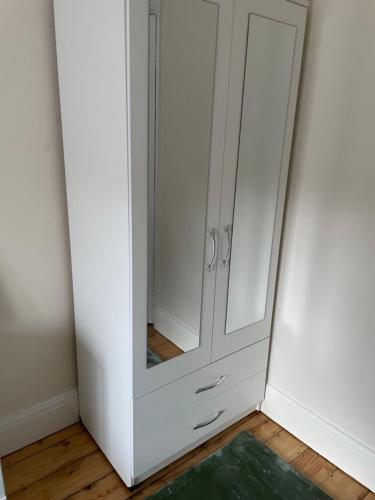 um armário branco com um espelho num quarto em B&B em Luton