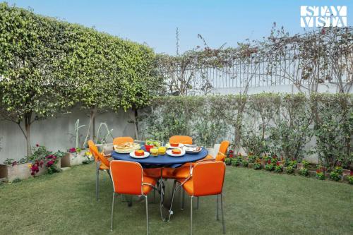 a table with orange chairs and food on it at StayVista's Velvet Whisper - Urban Retreat with Contemporary Decor, Cozy Balcony & Lawn in Amritsar