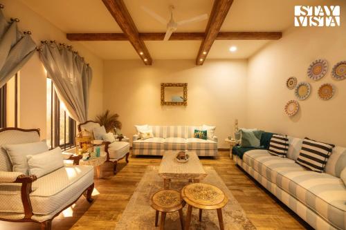 a living room with couches and a table at StayVista's Velvet Whisper - Urban Retreat with Contemporary Decor, Cozy Balcony & Lawn in Amritsar