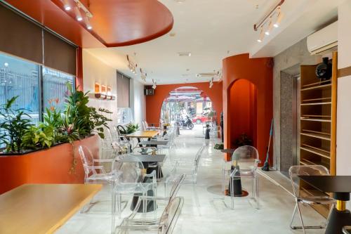 a restaurant with orange walls and tables and chairs at Quoc Cuong Hotel & Apartment Danang by Haviland in Da Nang