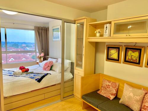 Schlafzimmer mit einem Bett mit einem Spiegel und einem Fenster in der Unterkunft DCondo Rattanathibet near MRT ดีคอนโด รัตนาธิเบศร์ in Ban Sai Ma