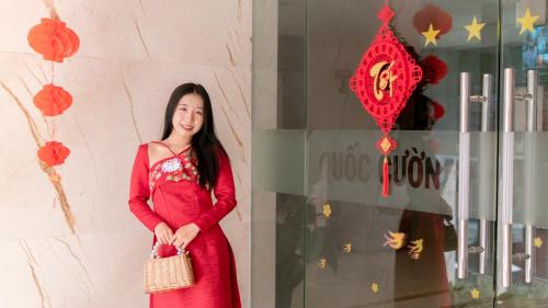 a woman in a red dress standing in front of a window at Quoc Cuong Hotel & Apartment Danang by Haviland in Da Nang