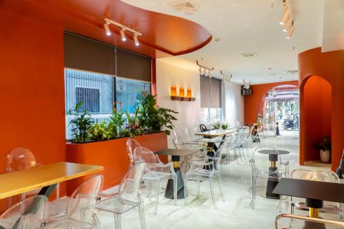 a restaurant with orange walls and tables and chairs at Quoc Cuong Center Da Nang Hotel by Haviland in Da Nang