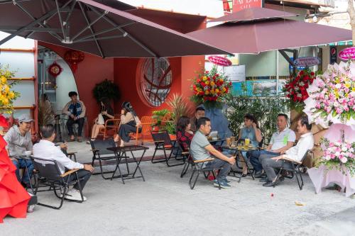 grupa ludzi siedzących przy stolikach przed restauracją w obiekcie Quoc Cuong Center Da Nang Hotel by Haviland w mieście Da Nang