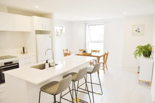 a white kitchen with a white counter and stools at Johnsonville Brand New Lovely townhouse in Wellington