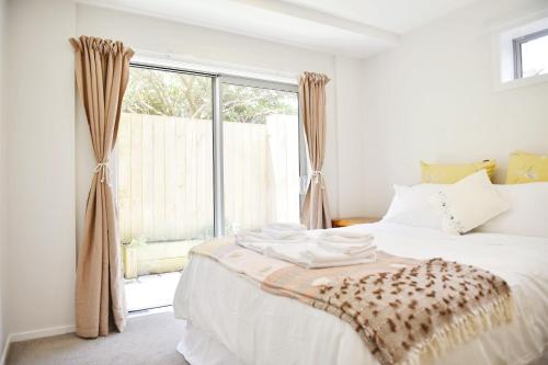 a bedroom with a white bed with a window at Johnsonville Brand New Lovely townhouse in Wellington