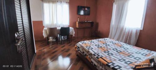 een slaapkamer met een bed, een tafel en een raam bij Chez Voyage R in Tôlagnaro