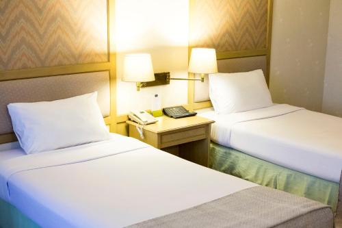 um quarto de hotel com duas camas e um telefone em โรงแรมมุกดาหารแกรนด์ 