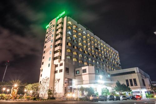 un edificio de hotel con una señal verde encima en โรงแรมมุกดาหารแกรนด์ 