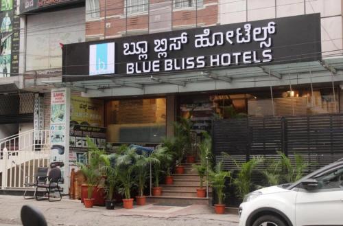 a blue bus hotel with plants in front of it at Blue Bliss Hotels By PPH Living Infantry Road in Bengaluru