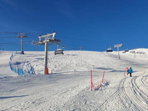 two people skiing down a snow covered ski slope at Evdo Apartments F2 Lovely Studio in Gudauri