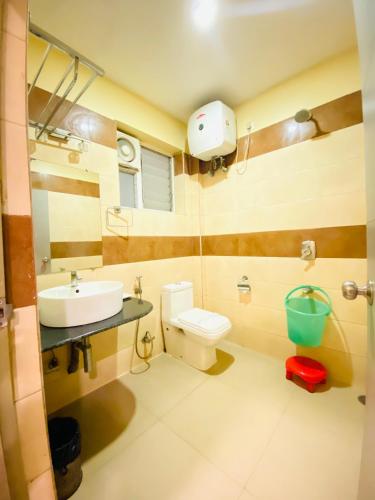 a bathroom with a sink and a toilet and a mirror at Hotel Saayein Residency in Siliguri