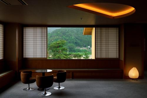 a room with a table and chairs and a window at 人肌の宿　川金 in Tonami