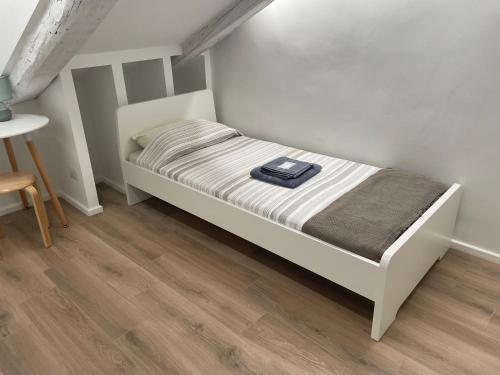 a small white bed in a room with a wooden floor at Mansarda (B13) Belfiore in Turin