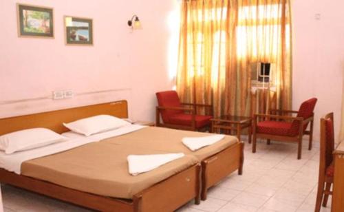 1 dormitorio con 1 cama y sillas en una habitación en Vasco Residency, en Vasco Da Gama