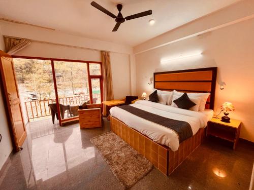 a bedroom with a large bed with a ceiling fan at Manali Hotel Beas River Retreat in Manāli