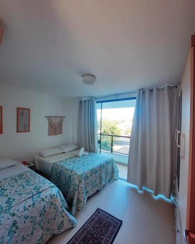 a bedroom with two beds and a large window at Imbassaí Solaris Ap Beach in Imbassai