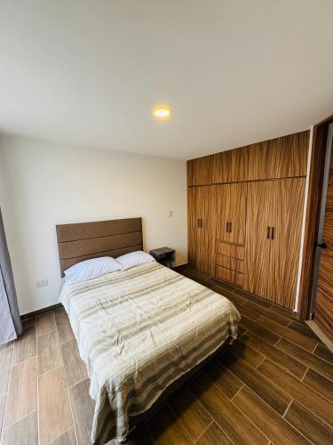 a bedroom with a large bed and a wooden cabinet at Casa en Fraccionamiento Privado con alberca in Cuautlancingo