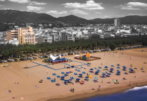 a beach with a bunch of chairs and people on it at Hotel Espanya by ALEGRIA in Calella
