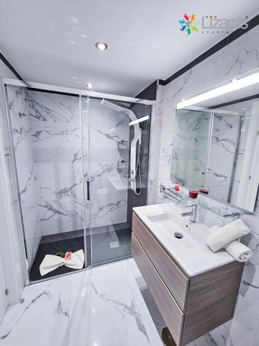 a white bathroom with a shower and a sink at 7Lizards - Ocean View Apartments in Puerto de Santiago
