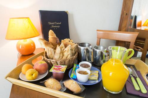 ein Tablett mit Essen auf einem Tisch mit Brot und Orangensaft in der Unterkunft Logis Hôtel Central in Montargis