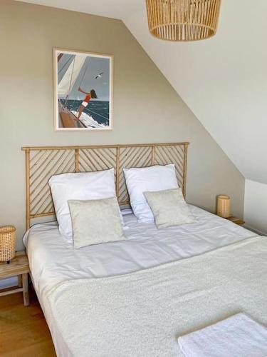 un lit avec des draps blancs et des oreillers dans une chambre dans l'établissement Maison neuve à 5 mins des plages, à Erdeven