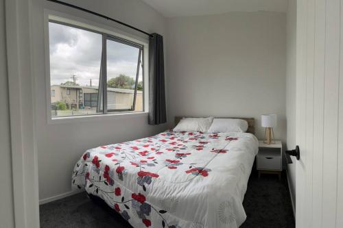 a bedroom with a bed with a flowered blanket and a window at Black Beauty - Spacious Family Retreat for 12 with Spa in Mangakino