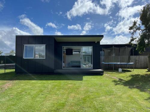 a black tiny house in a yard at Black Beauty - Spacious Family Retreat for 12 with Spa in Mangakino