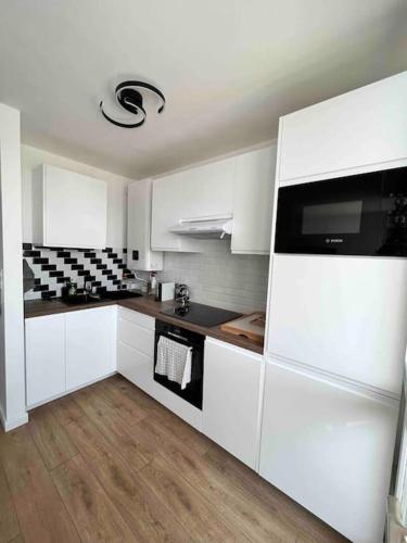 La cuisine est équipée de placards blancs et d'un réfrigérateur noir et blanc. dans l'établissement Le petit cocon de Kintana -Disney-Parking, à Meaux