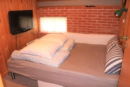 a bed in a room with a brick wall at Summerhouse Near The Limfjord And The Western Sea in Vestervig