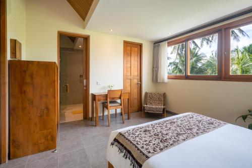 a bedroom with a bed and a table with a chair at The Vinaya Boutique Hotel in Ubud