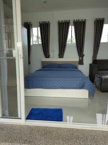 a bedroom with a bed with blue sheets and windows at Nongnuchs Homestay Queen Bed in San Sai