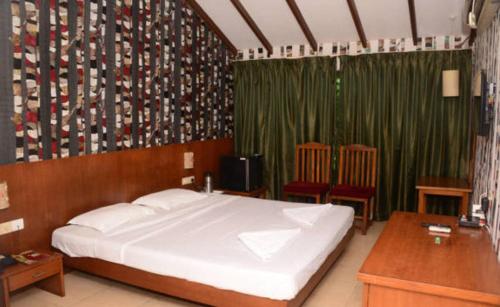 a bedroom with a large white bed and green curtains at Old Goa Residency in Old Goa