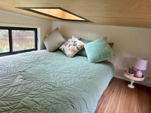 Un dormitorio con una cama grande con almohadas. en Tiny Home + Donkeys + Alpacas, en Tamborine