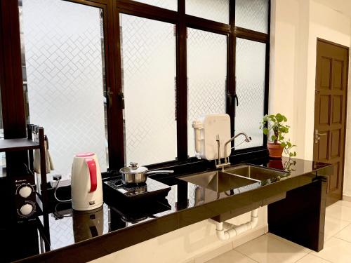 uma cozinha com um lavatório e um balcão com janelas em The Urban Lodge 1 em Kuala Terengganu