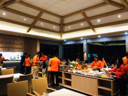 a group of people in orange shirts in a restaurant at Mayflower Grande Suite Hotel in Phitsanulok