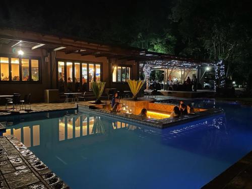 - une piscine avec des personnes assises la nuit dans l'établissement Manor Hills Guest Lodge, à Rustenburg
