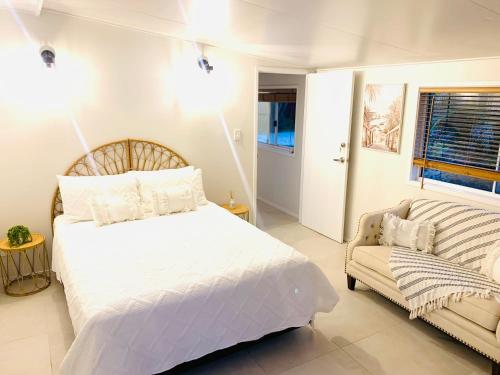 a bedroom with a white bed and a couch at Deluxe Queen Studio Fully Self Contained- Living, kitchenette, laundry, bedroom, bathroom, parking, Wifi, - Free shuttle Service in Gold Coast