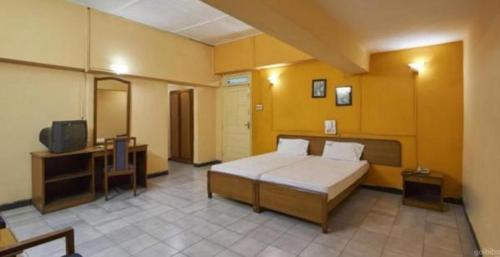 - une chambre avec un lit et une télévision dans l'établissement Mapusa Residency, à Mapusa