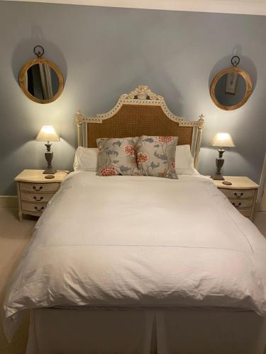 um quarto com uma cama branca com 2 candeeiros e espelhos em Maple House 