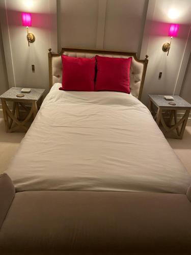 a large bed with a red pillow and two tables at Maple House 