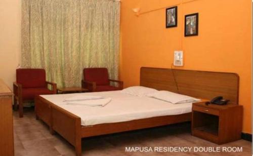 une salle d'hôpital avec un lit et deux chaises dans l'établissement Mapusa Residency, à Mapusa