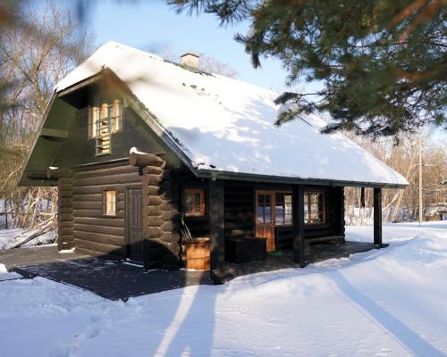 Cabaña de madera pequeña con nieve en el techo en River House, en Nītaure