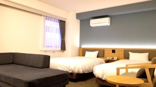 a hotel room with two beds and a couch at Kochi Sunrise Hotel in Kochi