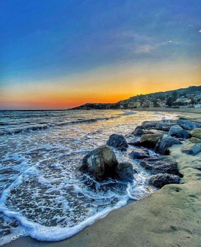a beach with rocks and the ocean at sunset at Alloggio U SPORTEGU DA E MONTI A GIAIA in Badalucco