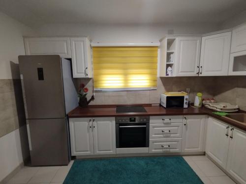 a kitchen with white cabinets and a refrigerator at Stan Ledine in Ledine
