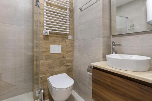 a bathroom with a white toilet and a sink at Next Green Aparthotel OFFICIAL in Batumi
