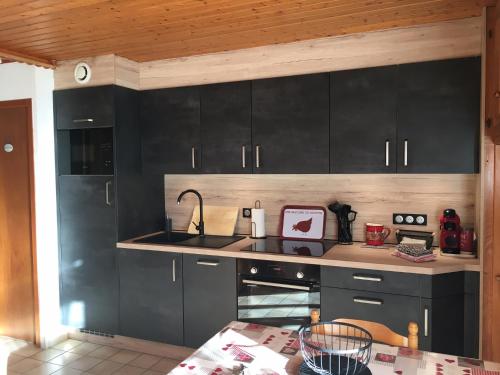 - une cuisine avec des placards noirs et un évier dans l'établissement Les Chenes Rouges, à Gérardmer