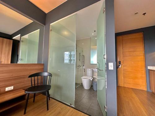 a bathroom with a toilet and a chair in it at Azumi Boutique Hotel in Manila