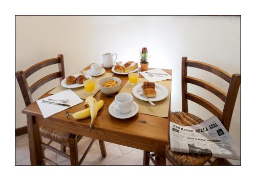 - une table en bois avec des aliments pour le petit-déjeuner et des boissons dans l'établissement B&B Casale Virgili, à Sienne